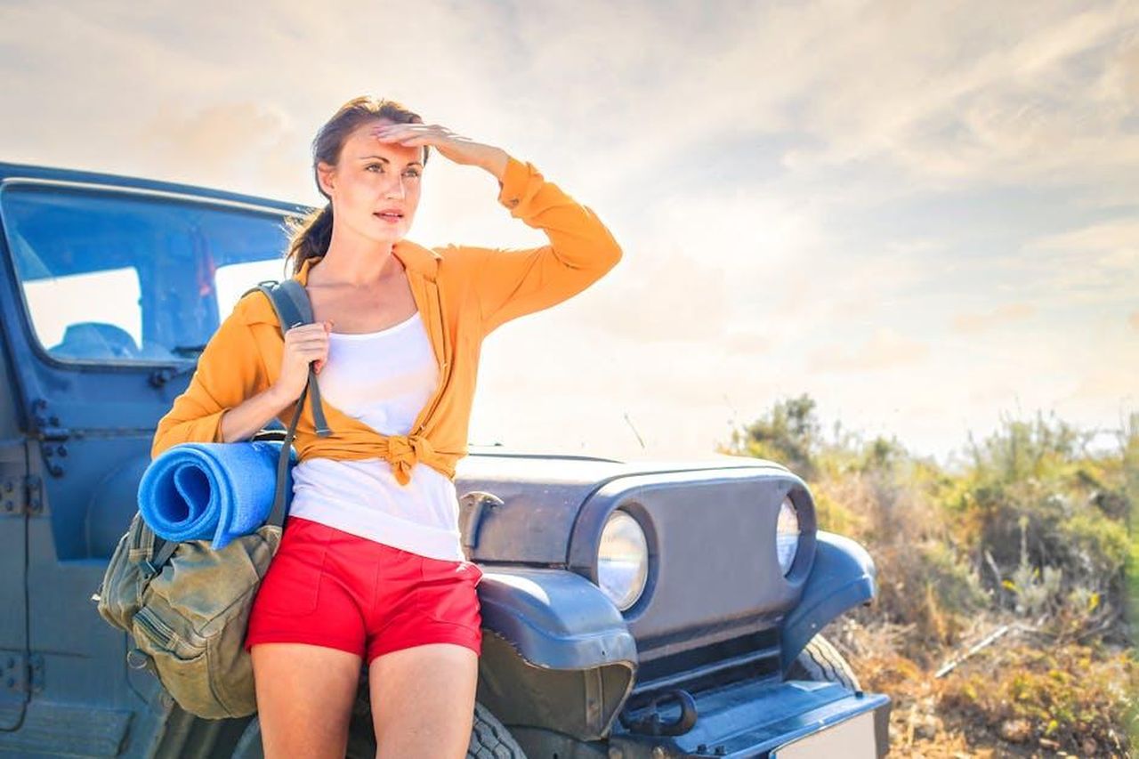 Jeep_Avenger_4xe_The_North_Face_Edition_VsCtovsITE - Veicoli24 Source: Andrea Piacquadio - pexels - Young woman looking into distance, next to off-road vehicle during summer travel adventure.