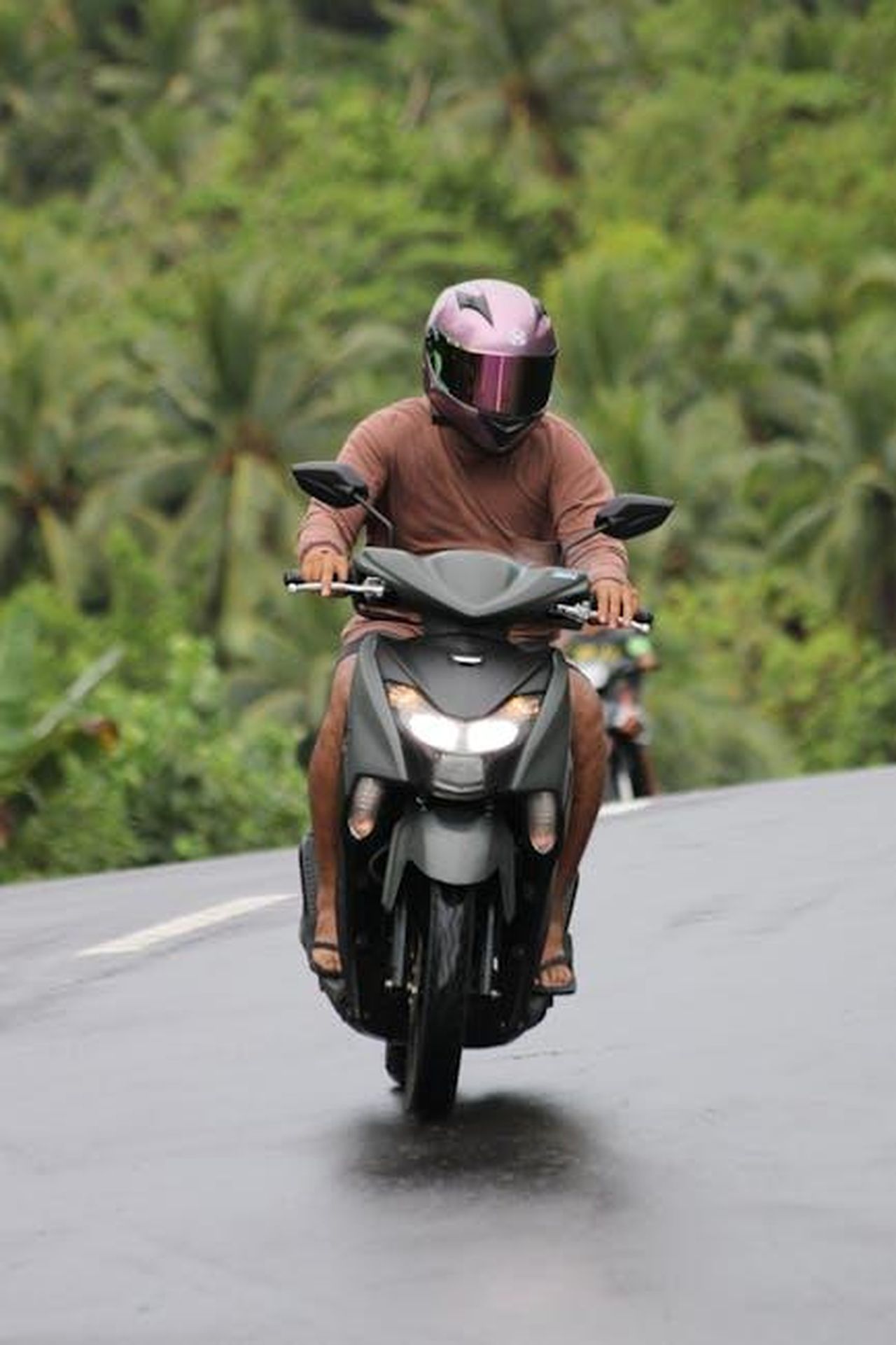 Limpegno_del_CSRC_per_la_sicurezza_della_mobilit_R2G9AXv3W6 - Veicoli24 Source: Tiwi Riders - pexels - A person riding a scooter through a tropical landscape wearing a helmet.