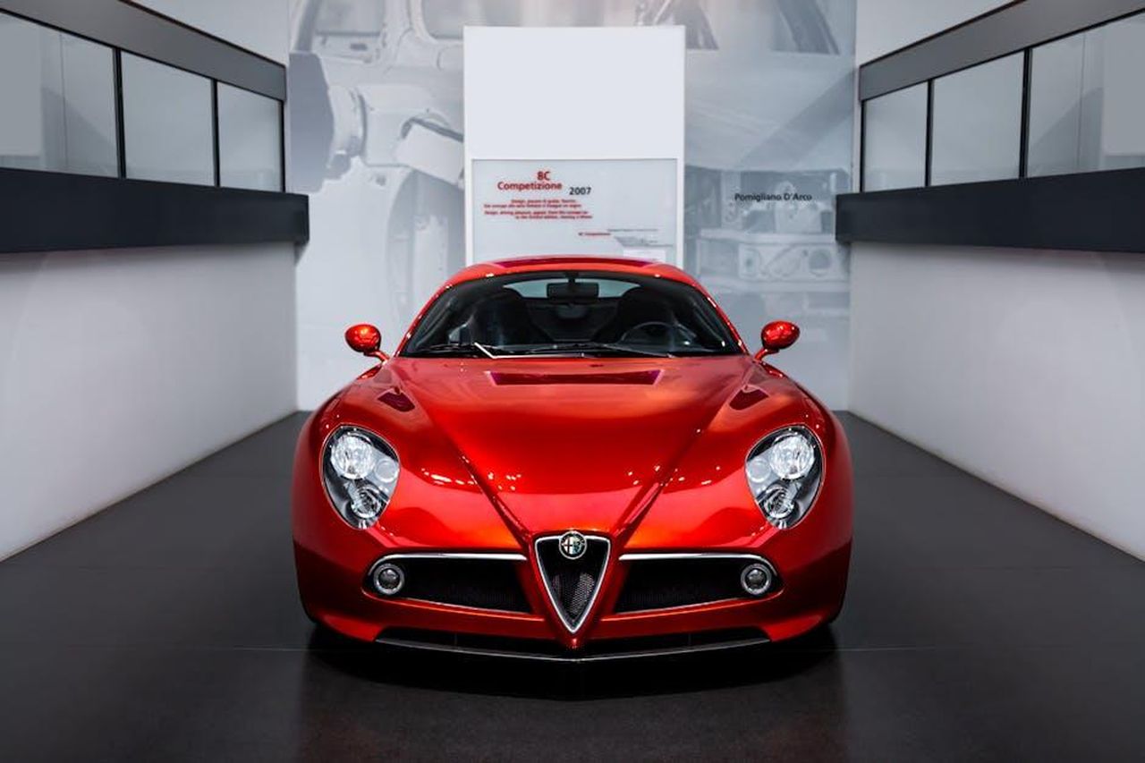 Modelli_di_successo_Tonale_e_Junior_8DUkNvydZ4 - Veicoli24 Source: Quentin Martinez - pexels - Elegant Alfa Romeo 8C Competizione displayed in a sleek, modern indoor showroom.