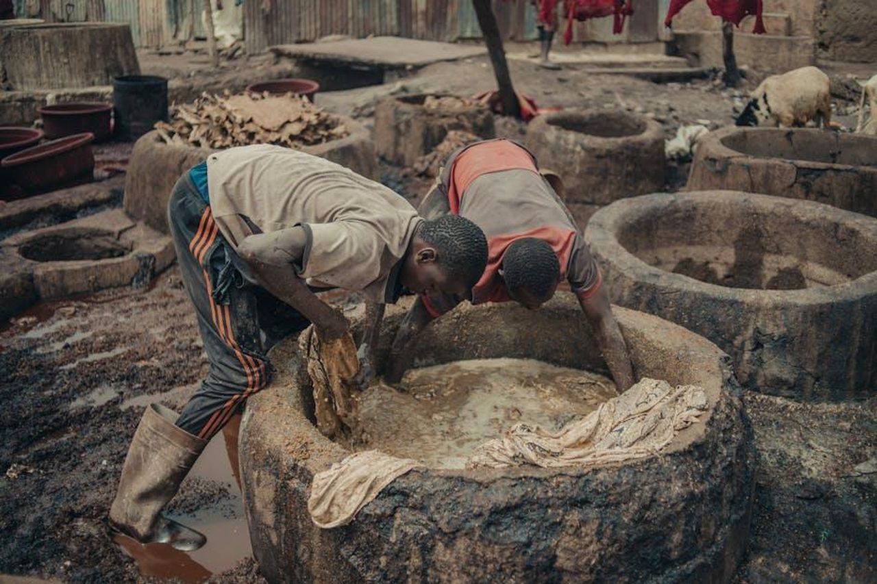 Workshop_per_artisti_in_Africa_Lagos_Dakar_Tangier_Nairobi_e_Cape_Town_sxXBWr5WPM - Veicoli24 Source: Gpop Yef - pexels - Two men work in a traditional fabric dyeing factory, using natural methods.
